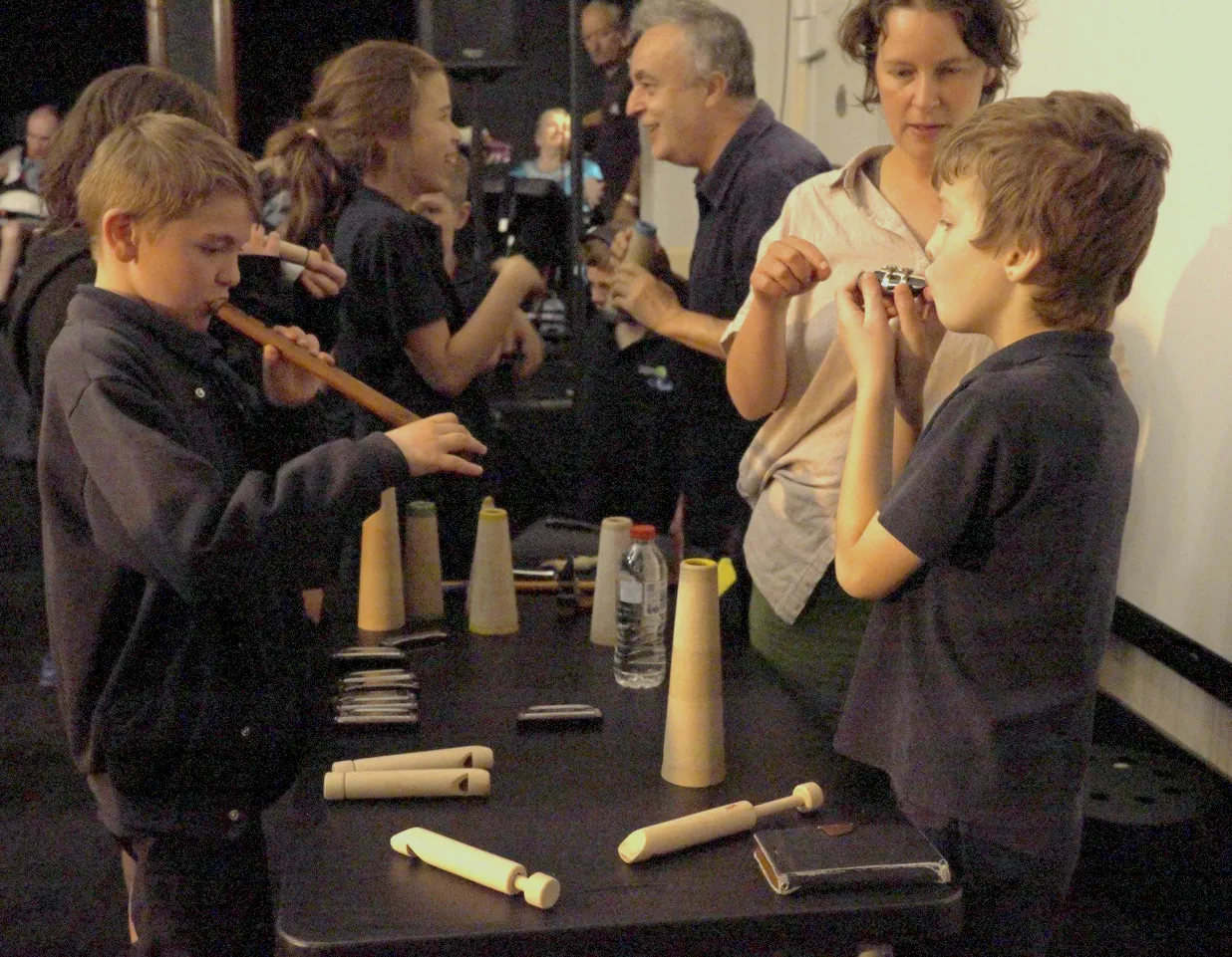 Children trying wooden flutes and hand-made instruments at a workshop table